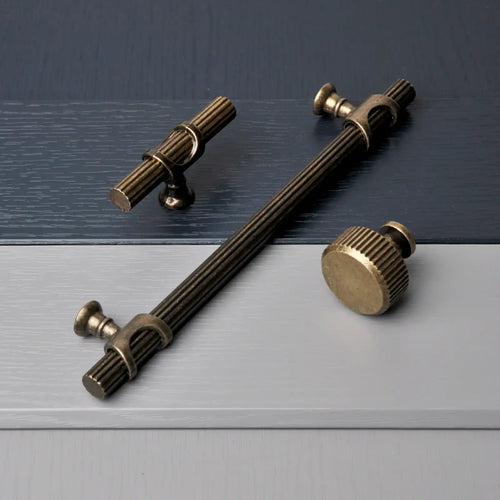 Antique brass cabinet handle with ribbed detailing and decorative end caps.